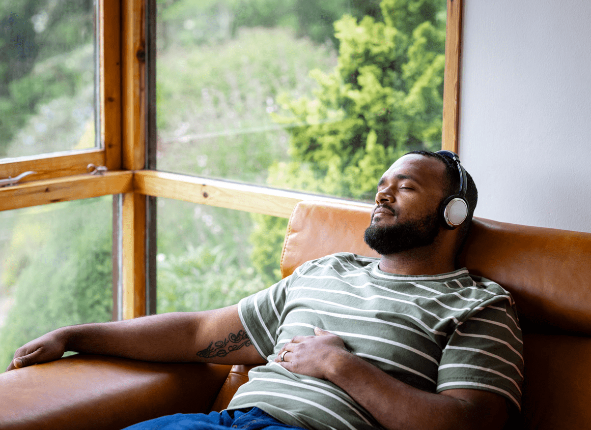 Man relaxing with headphones on sofa.