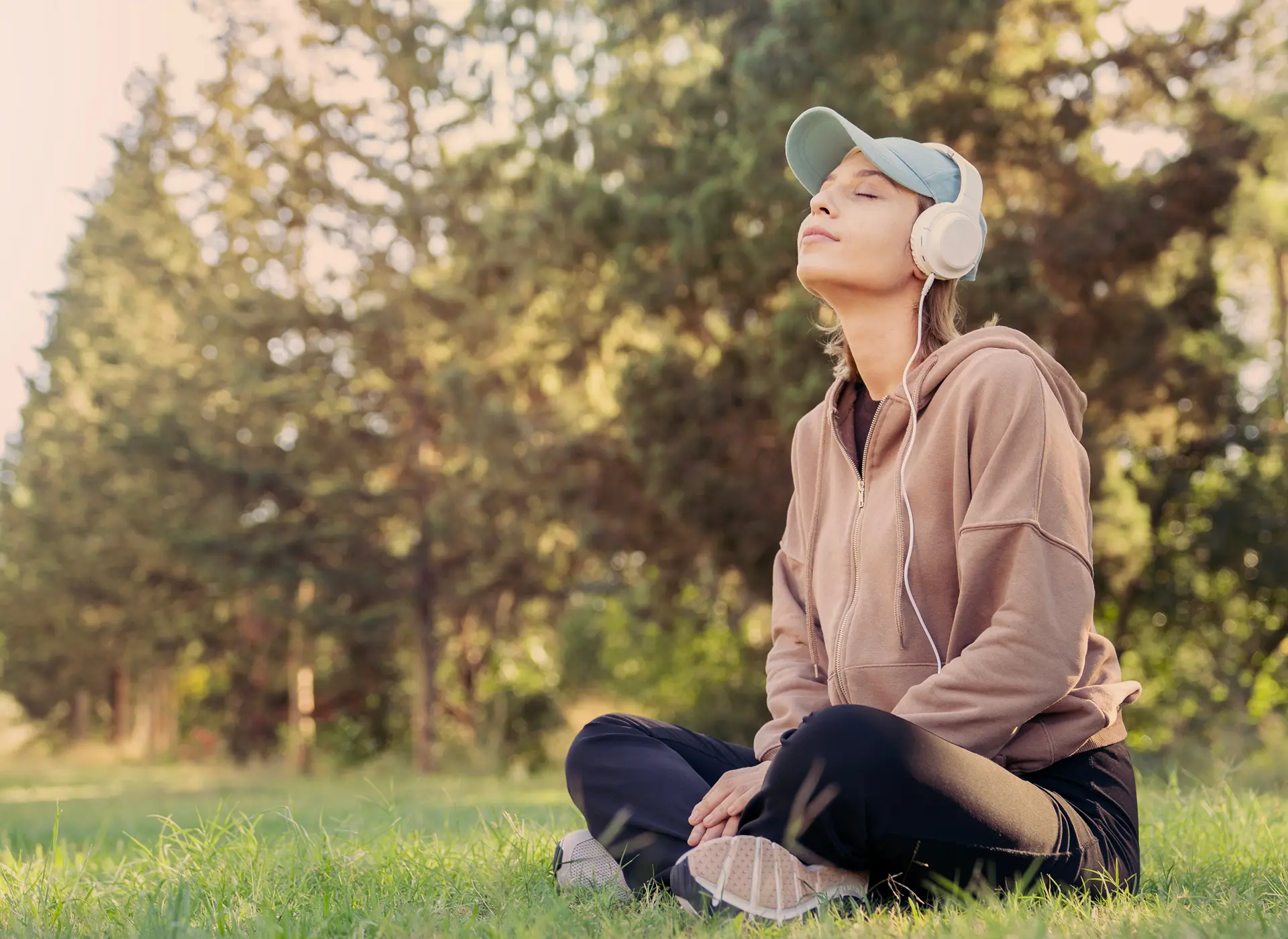 Woman meditating outdoors with headphones on.