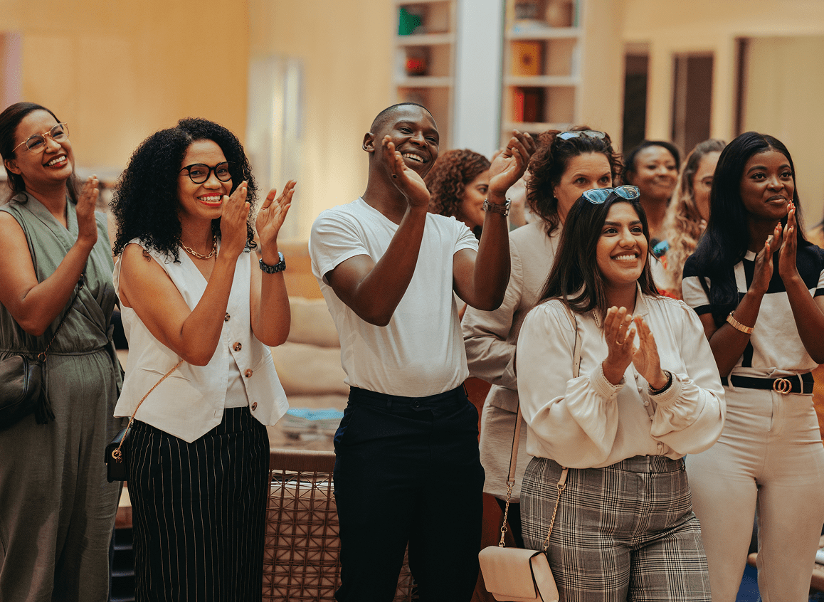 People clapping and smiling at an event.